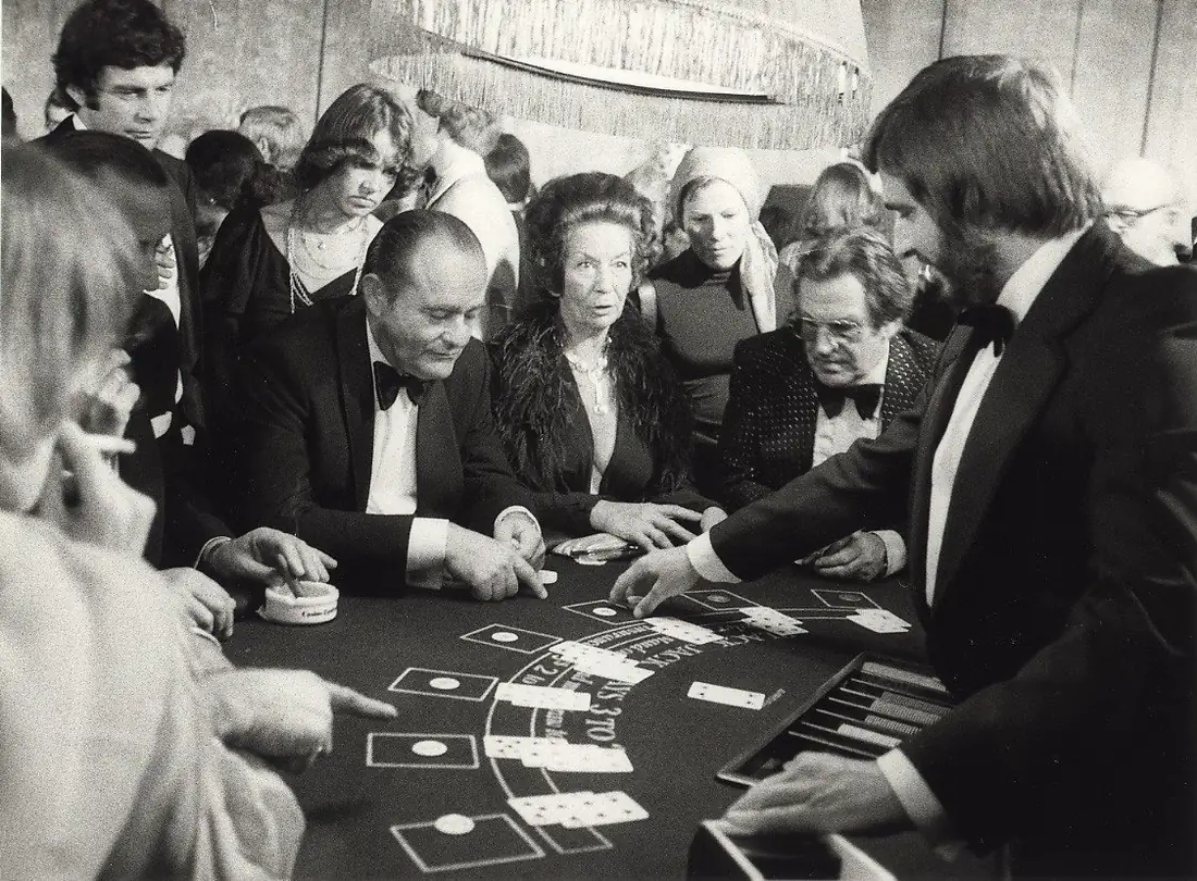 Fekete-fehér archív felvétel: vendégek és osztó egy blackjack-asztal körül a zandvoorti kaszinóban