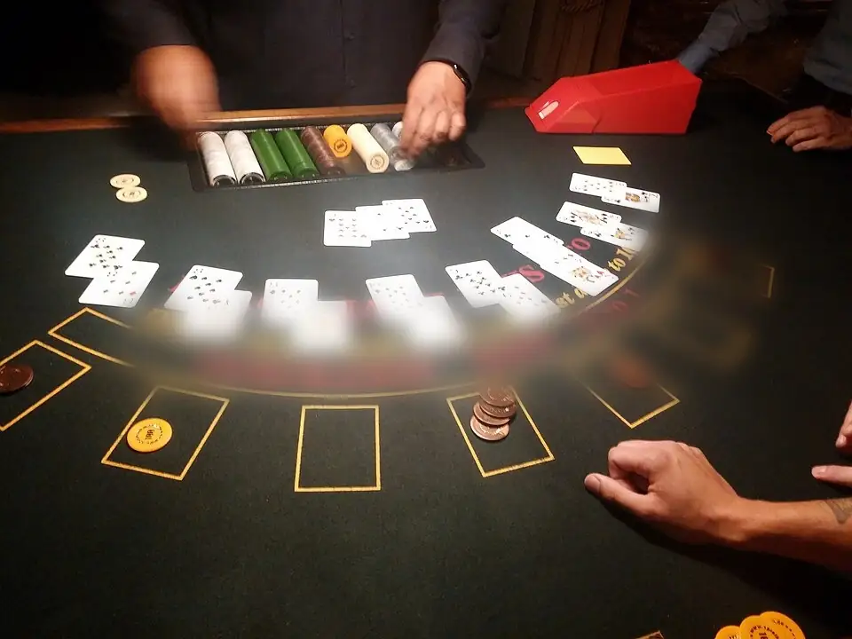 Zöld filces blackjack-asztal zsetontálcával, kártyaadagolóval és kiosztott lapokkal