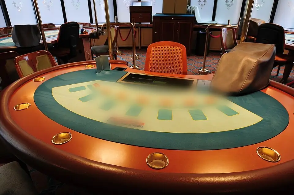 Üres félkörös blackjack-asztal osztószékkel és pohártartós peremmel