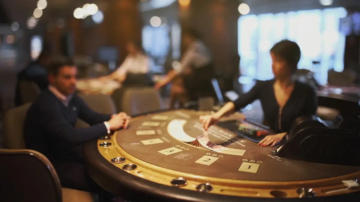 Osztó és játékos egy félkörös blackjack-asztalnál, kaszinóteremben